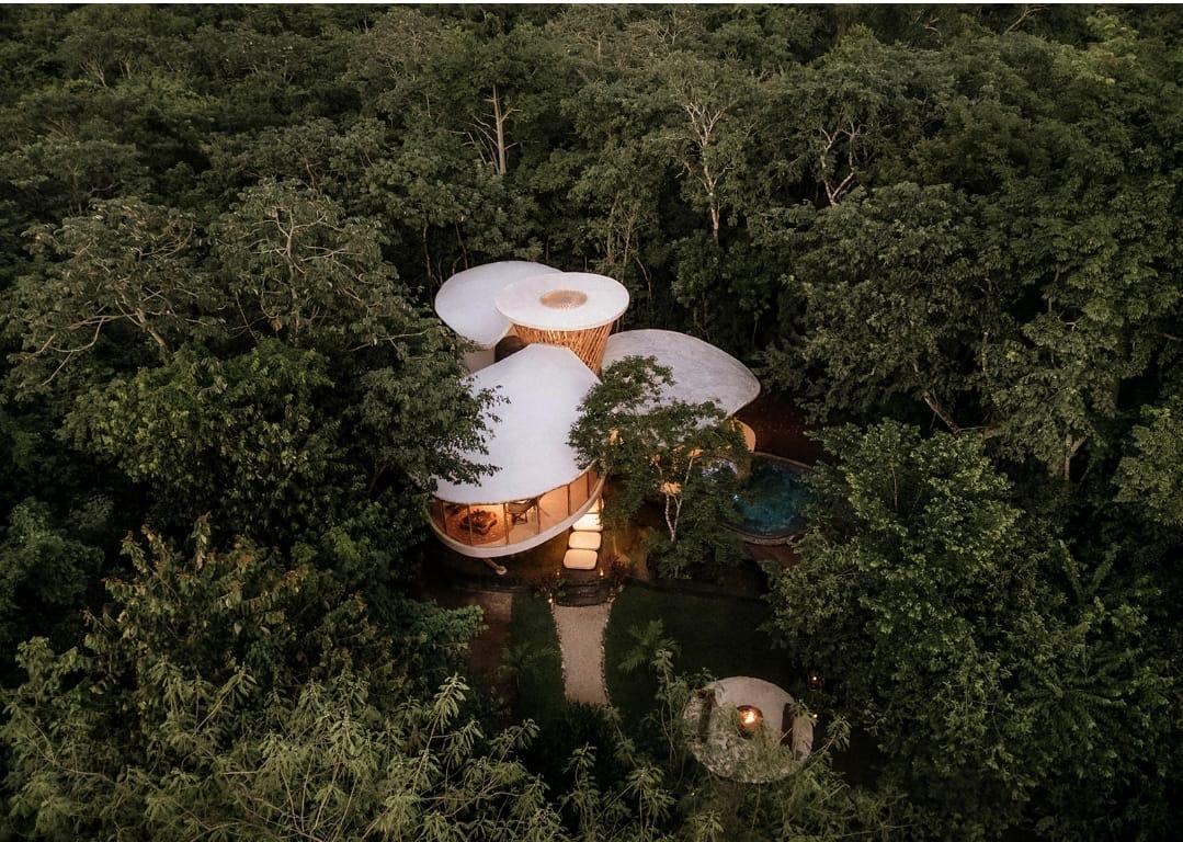 Villa de bambú iluminada al anochecer entre la selva